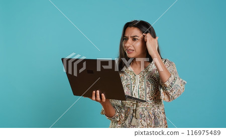 Irked woman fighting with coworkers during videocall on laptop, isolated over studio background. Outraged person arguing with colleagues during conversation on notebook, camera A Irked woman fighting with coworkers during videocall on laptop, isolated over studio background. Outraged person arguing with colleagues during conversation on notebook, camera A 116975489