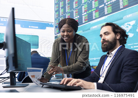 Team of diverse specialists review monthly cost and revenue elements on a computer, creating a financial projection for future improvements and success within the international organization. Team of diverse specialists review monthly cost and revenue elements on a computer, creating a financial projection for future improvements and success within the international organization. 116975491