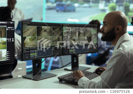 Middle eastern employee monitoring traffic surveillance footage on displays, using radar and CCTV system in observation room. Expert handling license plate recognition on security cameras. Middle eastern employee monitoring traffic surveillance footage on displays, using radar and CCTV system in observation room. Expert handling license plate recognition on security cameras. 116975526