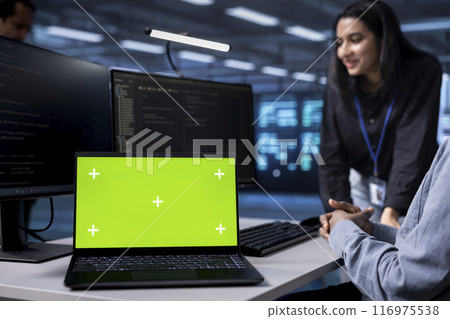 Focus on green screen notebook used by engineers in blurry background to oversee servers used for managing databases. Close up shot of mockup laptop used by IT specialists in data center Focus on green screen notebook used by engineers in blurry background to oversee servers used for managing databases. Close up shot of mockup laptop used by IT specialists in data center 116975538
