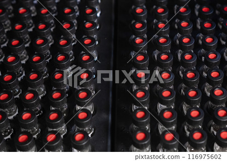 Top view of glass HPLC vials with black caps in autosampler. Top view of glass HPLC vials with black caps in autosampler. 116975602