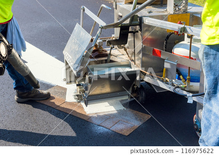 After asphalt is laid on road, workers apply markings signs 116975622