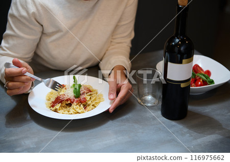 Person enjoying delicious pasta meal with red wine at dinner 116975662