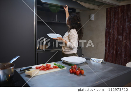 Woman preparing dinner in modern kitchen with fresh ingredients on counter Woman preparing dinner in modern kitchen with fresh ingredients on counter 116975720