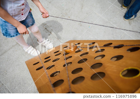 Child playing a wooden puzzle game outdoors on a sunny day Child playing a wooden puzzle game outdoors on a sunny day 116975896