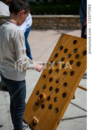 Boy playing with a wooden ring game outdoors during a sunny day 116975968