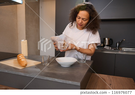 Woman preparing breakfast in modern kitchen with fresh bread and nuts Woman preparing breakfast in modern kitchen with fresh bread and nuts 116976077