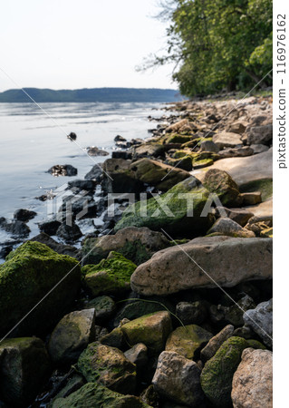 Close-up of a rocky shoreline along a lake at a local state park. Close-up of a rocky shoreline along a lake at a local state park. 116976162
