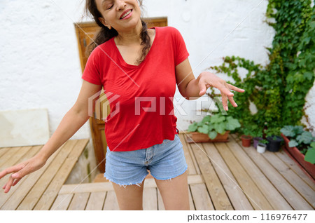Happy woman enjoying outdoor leisure time wearing red shirt and denim shorts 116976477