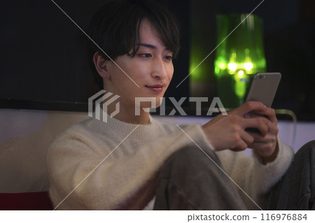 晚上家裡有智慧型手機的年輕人圖片 晚上家裡有智慧型手機的年輕人圖片 116976884
