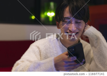 晚上家裡有智慧型手機的年輕人圖片 晚上家裡有智慧型手機的年輕人圖片 116977141
