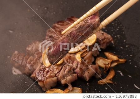 Steak, garlic steak, chopsticks up, lifting steak with chopsticks 116978888