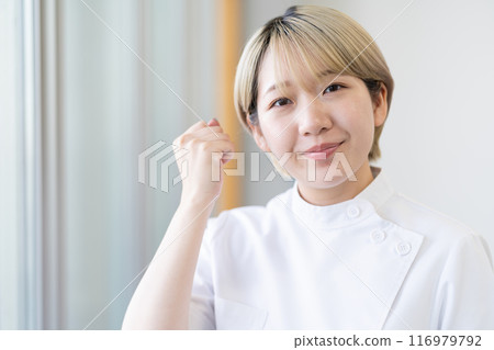 A young female chiropractor with short blonde hair wearing a Casey white coat (free hair color, work in your own way, work environment) A young female chiropractor with short blonde hair wearing a Casey white coat (free hair color, work in your own way, work environment) 116979792