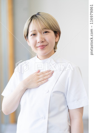 Casey 一位年輕的女性脊椎按摩師，金髮短髮，穿著白色外套（頭髮顏色自由，按自己的方式工作，工作環境） 116979861