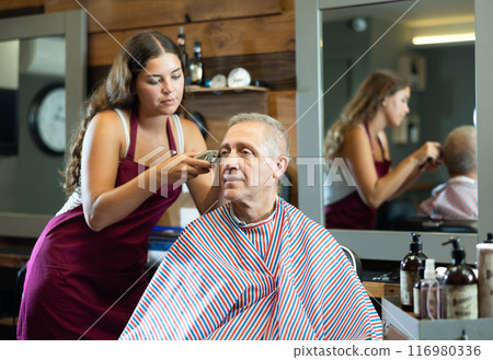 Hairdresser cutting hair of male client. Hairstylist serving client at barber shop Hairdresser cutting hair of male client. Hairstylist serving client at barber shop 116980336
