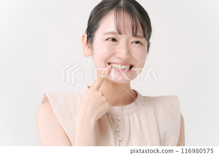 Young woman pointing to teeth Young woman pointing to teeth 116980575