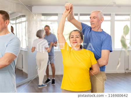 Elderly woman enjoying merengue with male partner in latin dance class Elderly woman enjoying merengue with male partner in latin dance class 116980642
