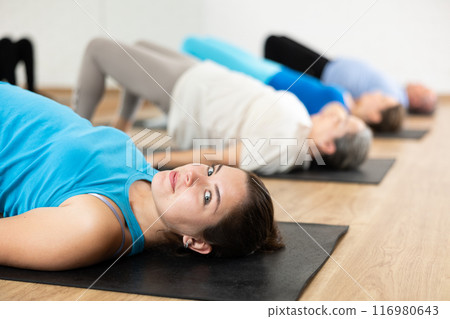 Smiling young girl performing glute bridge during workout 116980643