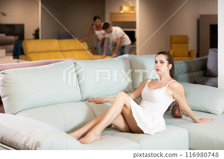 Young woman choosing convenient sofa in furniture shop Young woman choosing convenient sofa in furniture shop 116980748