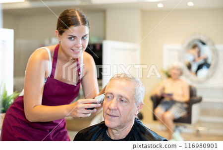 Female hairdresser working hair clipper with older man Female hairdresser working hair clipper with older man 116980901