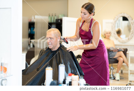 Female hairdresser working hair clipper with older man Female hairdresser working hair clipper with older man 116981077