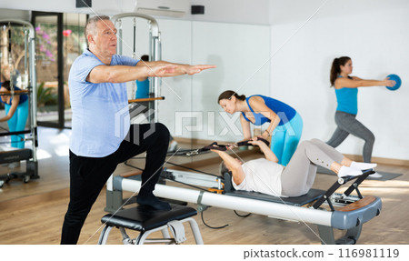 Elderly man doing gymnastics on pilates combo chair 116981119