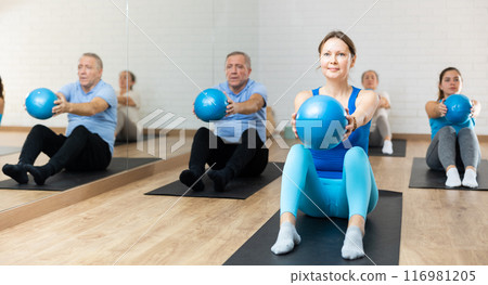 Middle-aged woman practicing pilates with ball in gym area 116981205
