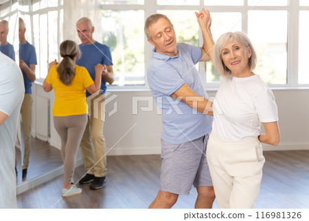 Senior man dancing bachata with female partner during group class 116981326