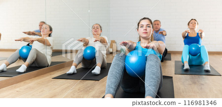 Young woman practicing pilates with ball in gym area 116981346