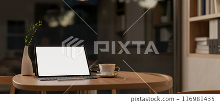 A tablet with a white-screen mockup and wireless keyboard on a wooden table in a room at night. A tablet with a white-screen mockup and wireless keyboard on a wooden table in a room at night. 116981435