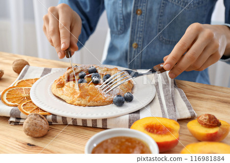 Fruit galette on plate and towel, man with cutlery at table on light background 116981884