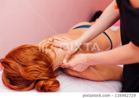 Close-up of masseur's hands massaging a client's shoulders. 116982729