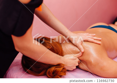 Close-up of masseur's hands massaging a client's shoulders. Close-up of masseur's hands massaging a client's shoulders. 116982730