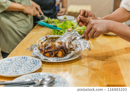 Group of friends enjoying roasted chicken dinner and vegetable salad. 116983203