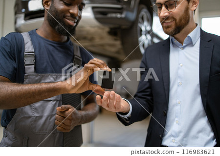 Mechanic and businessman exchanging electronic car part Mechanic and businessman exchanging electronic car part 116983621