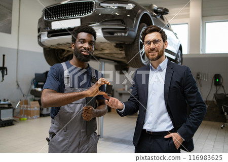 Mechanic and customer discussing car repair in garage Mechanic and customer discussing car repair in garage 116983625