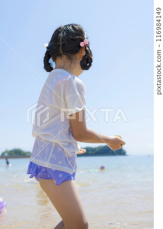 A girl playing in the sea during summer vacation A girl playing in the sea during summer vacation 116984149
