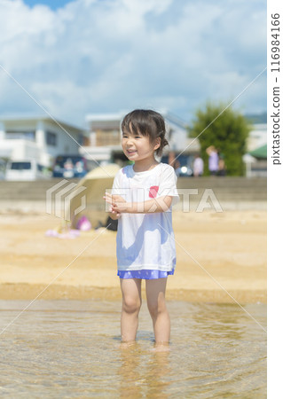 暑假期間，一個女孩在海裡游泳和玩耍 116984166