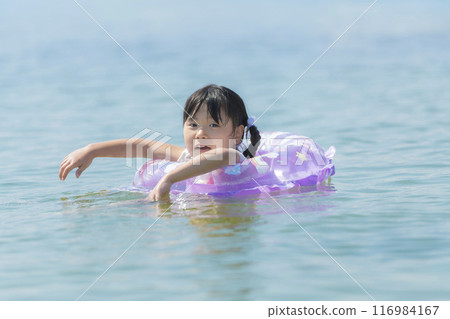 暑假期間,一個女孩在海裡游泳和玩耍 暑假期間,一個女孩在海裡游泳和玩耍 116984167