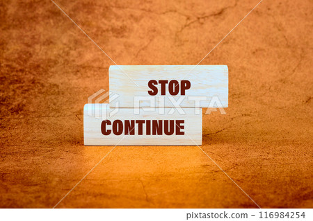 Conceptual symbol. Copy space. Stop or continue words written on wooden blocks on an abstract background 116984254