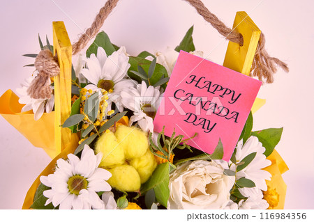 Canadian Independence Day celebration. Words Happy Canada Day on a sticker in a bouquet of flowers, close-up Canadian Independence Day celebration. Words Happy Canada Day on a sticker in a bouquet of flowers, close-up 116984356