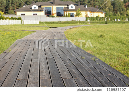 Paved deck walkway to cottage. Buildings, structures and utilities. Residential complex in nature in summer. Paved deck walkway to cottage. Buildings, structures and utilities. Residential complex in nature in summer. 116985507