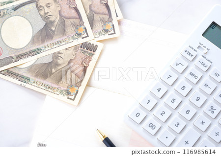 An open bank passbook, 10,000 yen notes, and a calculator on a table 116985614