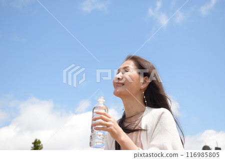 Profile of a smiling senior woman taking measures against heat stroke by hydrating Profile of a smiling senior woman taking measures against heat stroke by hydrating 116985805