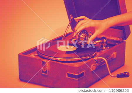 Old portable gramophone with female handA vintage gramophone, bathed in warm hues Old portable gramophone with female handA vintage gramophone, bathed in warm hues 116986293