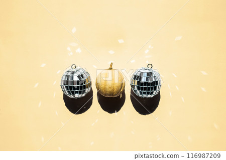 One tiny pumpkin and some disco balls on a row. 116987209