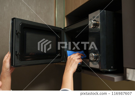 woman hand using microfiber cloth to cleaning microwave oven 116987607