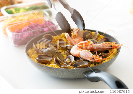 Use tongs to arrange shrimp on paella 116987615
