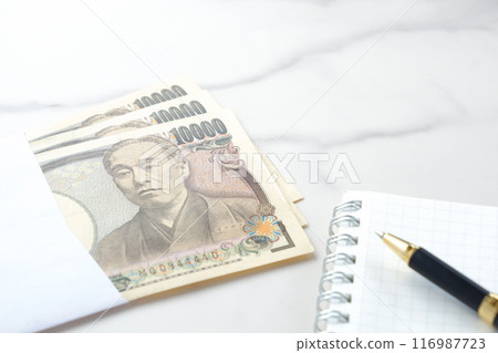 印有福澤諭吉肖像的 10,000 日元紙幣、記事本和筆 116987723