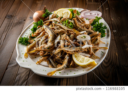 Anchovies in the menu of restaurants and cafes of Turkish cuisine on a large dish with herbs, lemon and onion, close-up 116988105